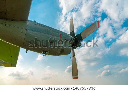 Aircraft Propeller and Spinner Engine on Airplane Wing Against Cloudy Blue Sky. Four Blade Aircraft Propeller. Royalty-Free Stock Photo #1407557936