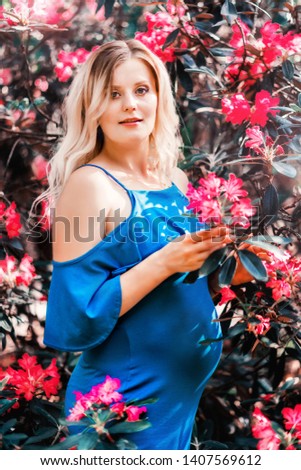 Pregnant woman on the background of a bush with red flowers