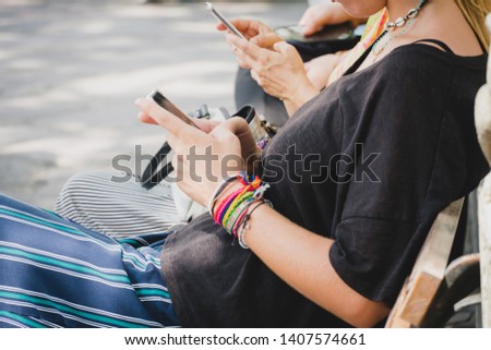 Hand of tourist Woman holding smartphone . Female reading and type text message on telephone during sitting inside the park