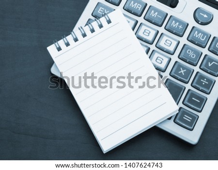Calculator and notebook with blank page for text message on table