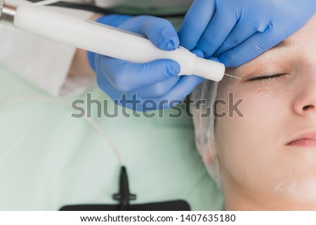 Closeup cropped image of female patient having treatment with plasma pen for firming eyelids Royalty-Free Stock Photo #1407635180