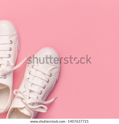 White female fashion sneakers on pink background. 