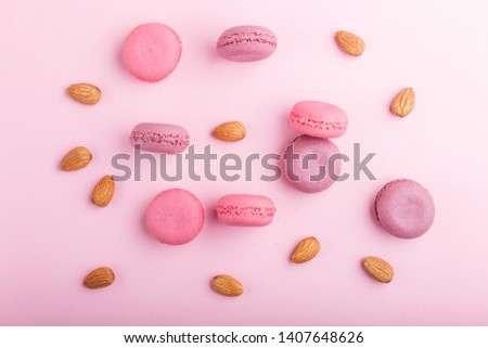 Purple and pink macaron or macaroon cakes with almonds on pastel pink background. Morninig, spring, fashion composition. Flat lay, top view, pattern.