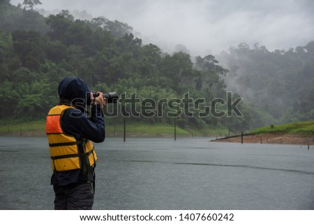 Tourists take pictures of mountains in the rain.