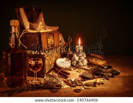Closeup on treasure still life, luxury vintage accessories, pirates booty, bottle with rum, fish skeleton, cigars and golden coins, dangerous adventure concept