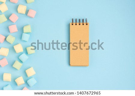 Blue background with marshmallow and blank notepad. Place for your text. Cozy sweet background