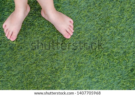Small baby feet on the green grass. Copy space.