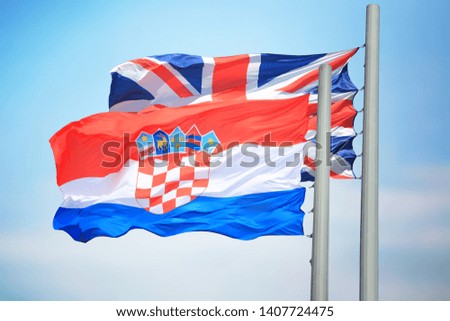 The Croatian and British flags against the background of the blue sky
