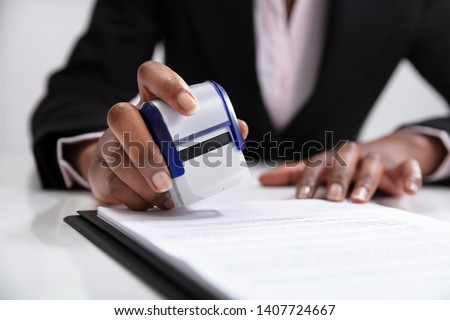 Close-up Of Businesswoman Putting Stamp On Documents In The Office Royalty-Free Stock Photo #1407724667