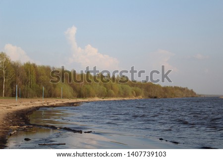 photo White lake. on water big the blue waves of . Sand beach. Forth is wood. The trees have green leaves.Spring time.The sky is blue with white clouds.Sunny weather.Beautiful White lake in the Vologd
