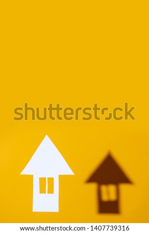 a small house made of cardboard casts a shadow on a bright colored background