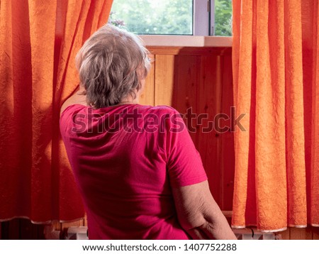 beautiful pensioner opens window.
elderly woman in pink blouse is waiting for arrival of social worker. Senior lady has headache and heart ache. Help for elderly and people with disabilities