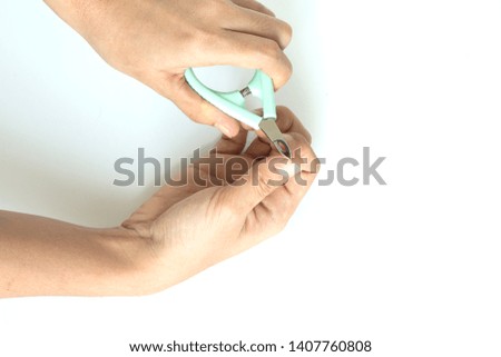 Woman use nail clipper cutting their thumbs nail on white background