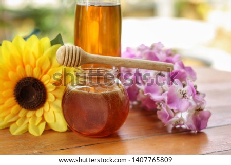 Close up of fresh honey in glass jar with honey dipper and sunflower on a wooden table.Sweet taste and natural product for good health.Have copy space.