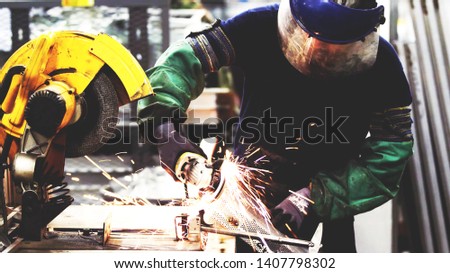 Heavy industry worker cutting steel with electric grinder machine in industrial factory manufacture, wearing safety equipment