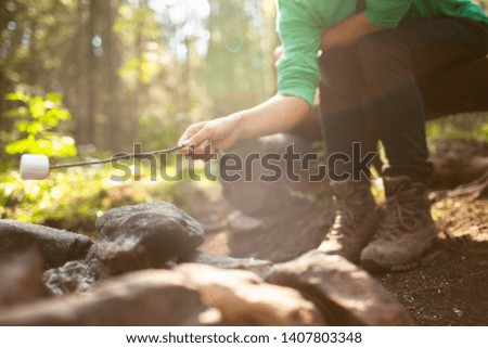 A girl sits by the fire in the woods and roasting marshmallows