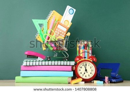 School supplies with books and alarm clock on chalkboard background