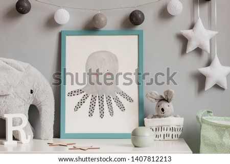 Stylish scandinavian childroom with blue mock up poster frame, toys, boxes, plush elephant and rabbit. Hanigng stars and cotton balls on the gray background wall. Cozy home decor. White shelf concept.