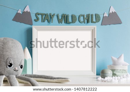 Cozy scandinavian newborn baby room with mock up poster frame, plush octopus ,mint crayon, boxes, stars and children accessories. Stylish interior with blue walls and haniging inscription . Template.