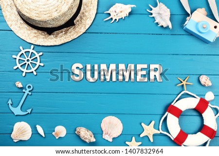 Word Summer with seashells, hat and lifebuoy on blue wooden table