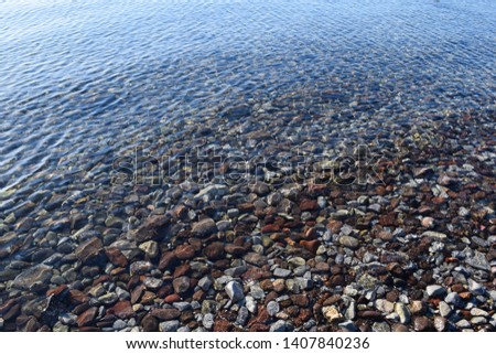 Cleanest shore of Aegean Sea. Stones under the clear water. Background, texture and wallpaper in high resolution
