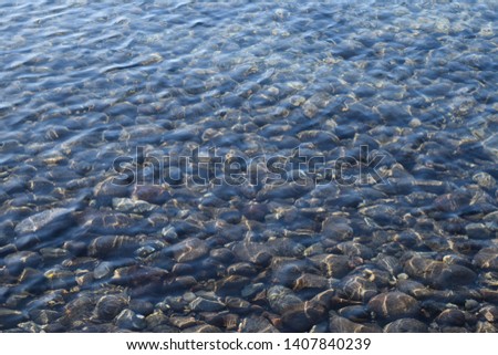 Cleanest shore of Aegean Sea. Stones under the clear water. Background, texture and wallpaper in high resolution