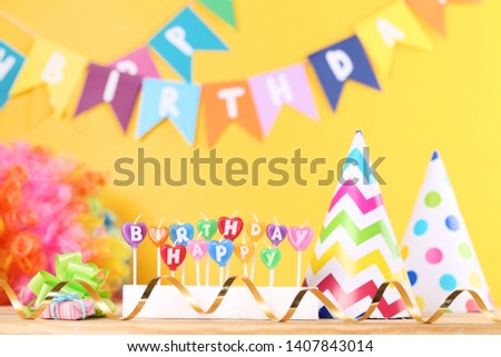 Happy Birthday candles with party decorations on yellow background