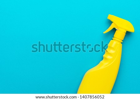 cleaning spray on the turquoise blue background with copy space. flat lay image of yellow plastic dispenser