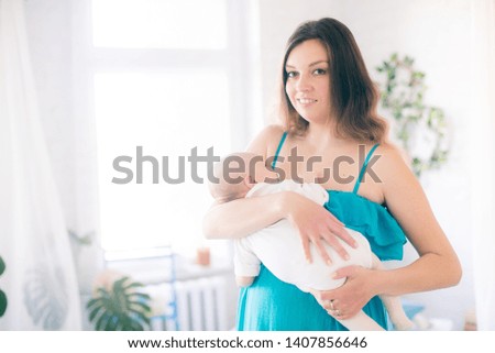 
Young mother and little cute baby at home on bed with blue bedspread and pillows