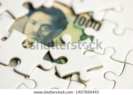 White jigsaw puzzle covering on blurry Japan money yen