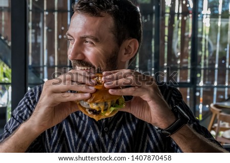 Man eating delicious burger and french fries in restaurant
