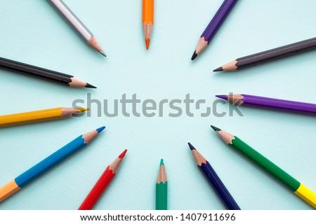 Color pencils in arrange in color wheel colors on blue background. Vie top. A free place for text.