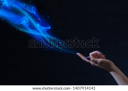 magic hand, conceptual image with glow on a black background, blue magic, magical dust, the power of the sorceress, female charms