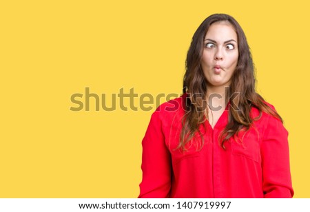 Beautiful plus size young business woman over isolated background making fish face with lips, crazy and comical gesture. Funny expression.