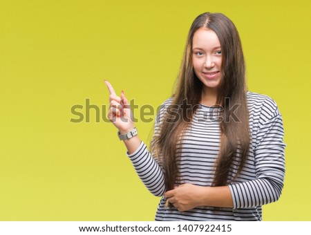 Young beautiful caucasian woman over isolated background with a big smile on face, pointing with hand and finger to the side looking at the camera.