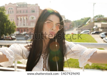 Young smiling girl making selfie on the background of the city
