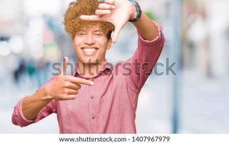 Young handsome business man with afro hair smiling making frame with hands and fingers with happy face. Creativity and photography concept.