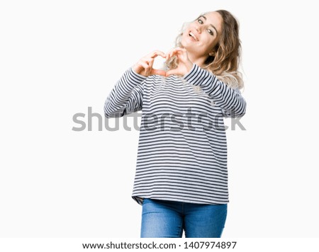 Beautiful young blonde woman wearing stripes sweater over isolated background smiling in love showing heart symbol and shape with hands. Romantic concept.