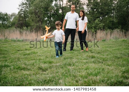 Father, mother and son playing with toy airplane in the park. friendly family. People having fun outdoors. Picture made on the background of the park and blue sky. concept of a happy family.