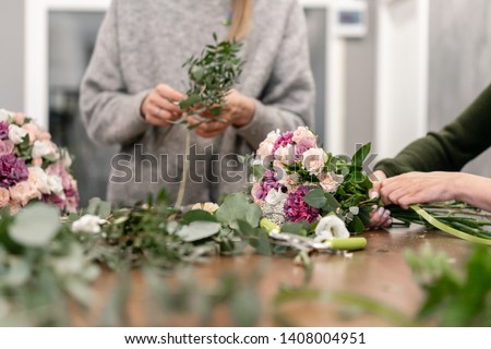 Close-up flowers in hand. Florist workplace. Woman arranging a bouquet with roses, carnation and other flowers. A teacher of floristry in master classes or courses Royalty-Free Stock Photo #1408004951