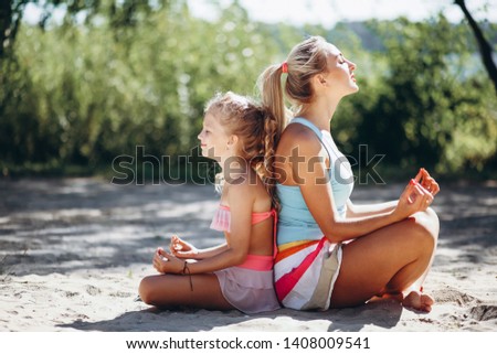 Mother and daughter at the beach practising yoga