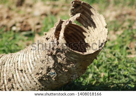 Dried muddy pipe on the ground, abstract object covered with mud