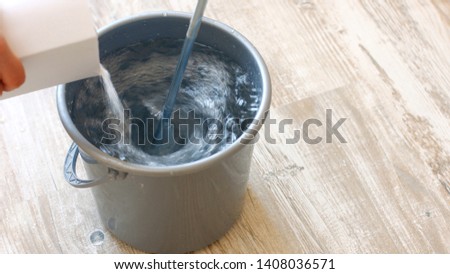 Builder knead glue for wallpapering. Pouring wallpaper paste in to a bucket of water and stirring with a stick. House repair concept. Royalty-Free Stock Photo #1408036571