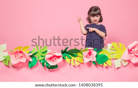 Portrait of a little girl on a summer pink background with paper flowers, place for text, summer advertising concept