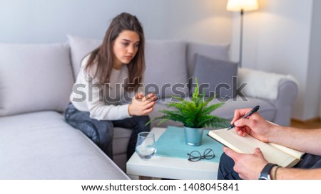 Depressed woman. Depressed young woman wearing yellow shirt feeling at a loss while visiting therapist. Psychotherapist working with young woman in light office 