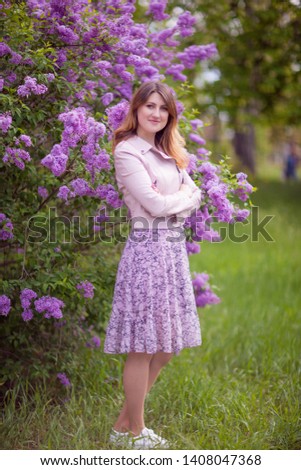 Young beautiful woman in a pink dress on a lilac background. Spring outdoors park. 