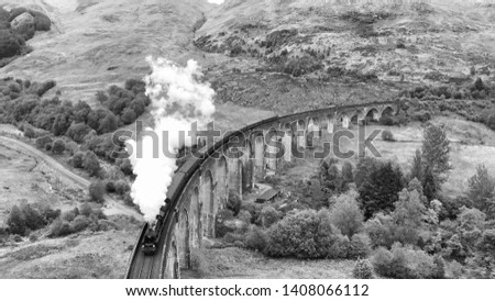 Steam Train crossing the Glenfinnan Viaduct, aerial view by drone, black and white filter - Scotland, UK