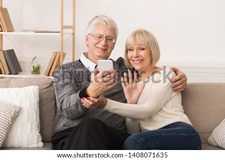 Happy Senior Couple Making Video Call On Phone And Waving To Caller Royalty-Free Stock Photo #1408071635