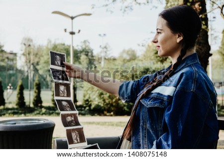 A pregnant woman looks at the photo of ultrasonography or diagnostic sonography. The concept of pregnancy, expect a child. The joy of being a future mother, problems during pregnancy.
