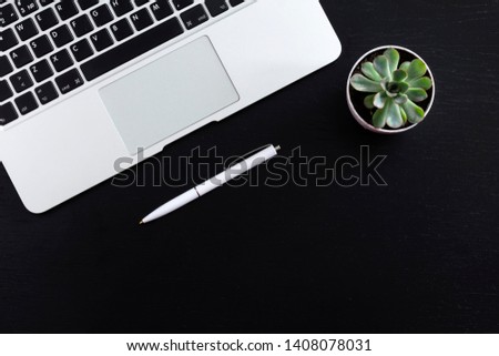 Office textured black desk table with laptop, succulent and pen. Top view of stylish workspace with copyspace. Flat lay.